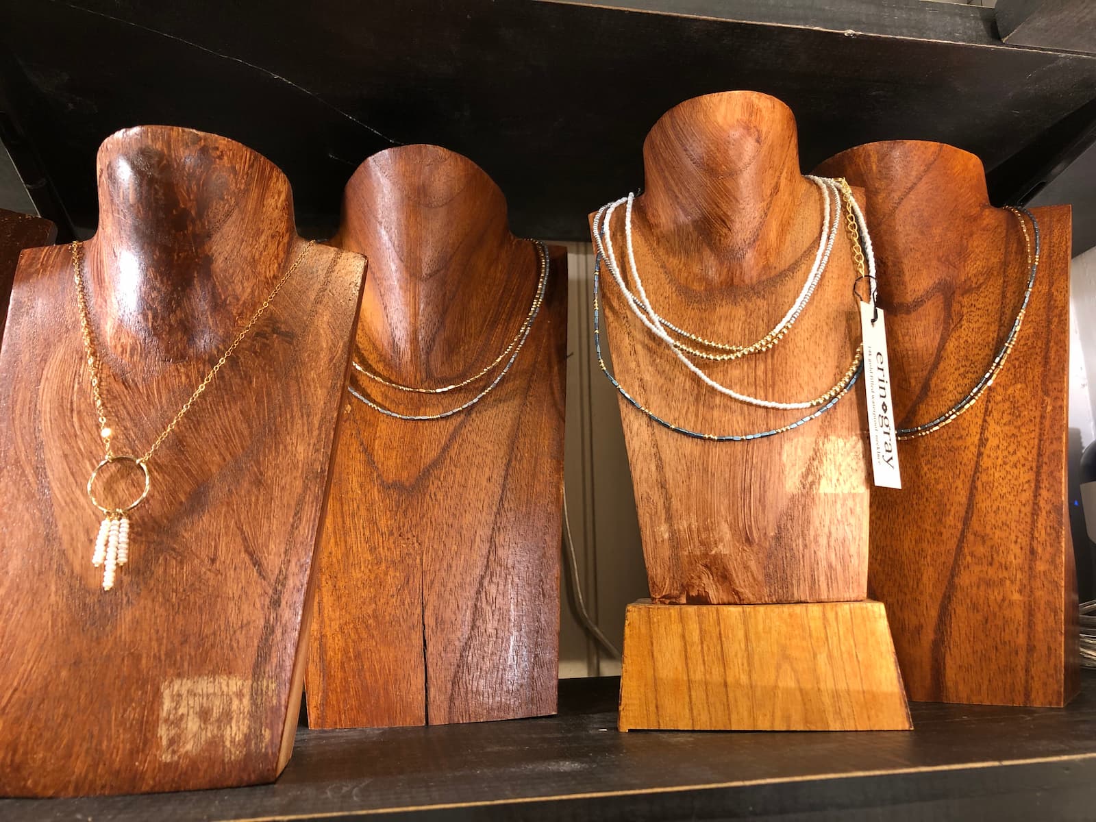 Stone necklaces on display on wooden figures